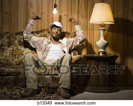 Man sitting on sofa under light bulb pointing up View Large Photo Image Stock Photo - Man sitting on sofa under light bulb pointing up. Fotosearch