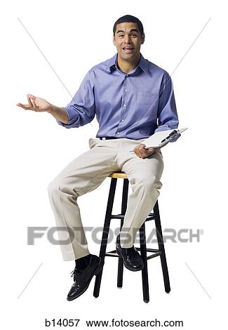 Man sitting on stool with clipboard gesturing View Large Photo Image Stock Photo - Man sitting on stool with clipboard gesturing. Fotosearch