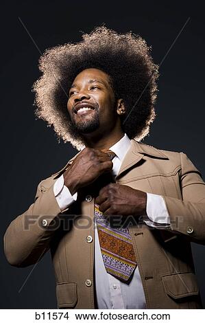 Man with an afro in beige suit adjusting necktie View Large Photo Image Picture - Man with an afro in beige suit adjusting necktie. Fotosearch
