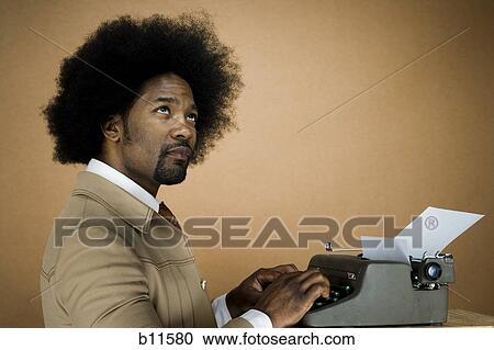 Man with an afro in beige suit typing on a typewriter View Large Photo Image Stock Image - Man with an afro in beige suit typing on a typewriter. Fotosearch