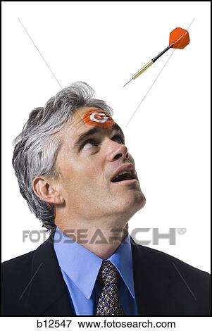 Stock Photo - Man with bull's-eye on forehead and dart coming toward him. Fotosearch