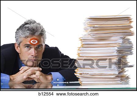 Picture - Man with bull's-eye on forehead with stack of papers. Fotosearch
