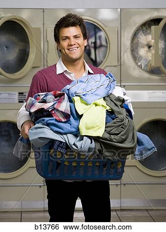 Man with clothing in laundry basket at Laundromat smiling View Large Photo Image Stock Photograph - Man with clothing in laundry basket at Laundromat smiling. Fotosearch