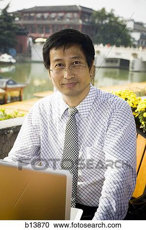 Stock Image - Man with laptop in business attire outdoors. Fotosearch