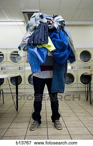 Man with pile of clothing in Laundromat View Large Photo Image Stock Photo - Man with pile of clothing in Laundromat. Fotosearch