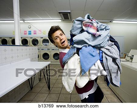 Stock Photo - Man with pile of clothing in Laundromat. Fotosearch