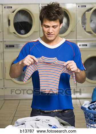 Man with small shirt at Laundromat View Large Photo Image Stock Photo - Man with small shirt at Laundromat. Fotosearch