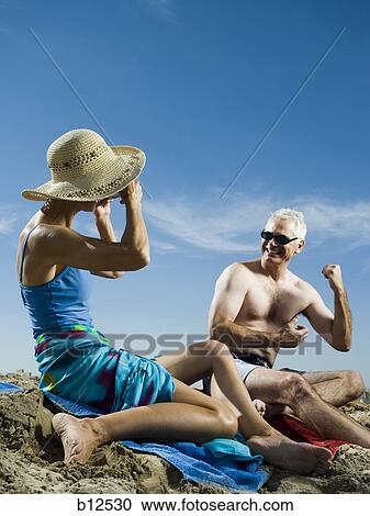 Stock Image - Mature couple relaxing at the beach. Fotosearch