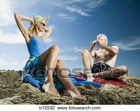 Stock Image - Mature couple relaxing at the beach. Fotosearch