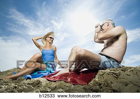 Stock Image - Mature couple relaxing at the beach. Fotosearch