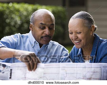 Stock Image - Mature man and woman looking at map outdoors smiling. Fotosearch