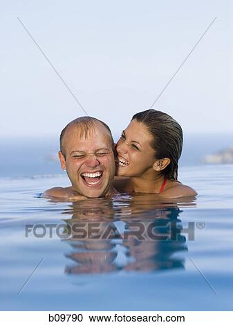 Stock Image - Mid adult couple smiling together in a swimming pool. Fotosearch