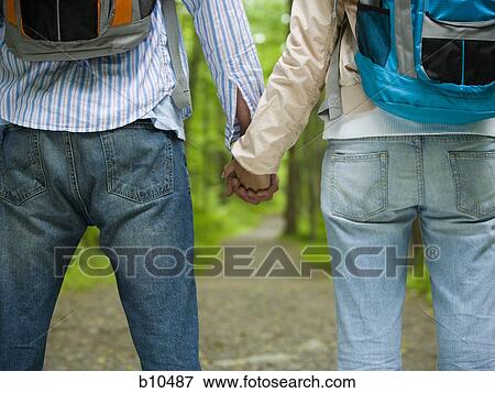 Mid section view of a young couple holding hands and standing View Large Photo Image Stock Photo - Mid section view of a young couple holding hands and standing. Fotosearch
