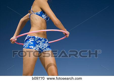 Mid section view of a young woman playing with a hula hoop View Large Photo Image Stock Image - Mid section view of a young woman playing with a hula hoop. Fotosearch