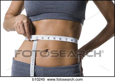 Mid section view of a young woman measuring her waist with a measuring tape View Large Photo Image Stock Photography - Mid section view of a young woman measuring her waist with a measuring tape. Fotosearch