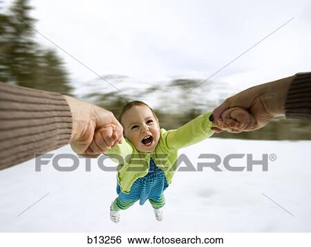 Stock Photograph - Mother swinging child outdoors in winter. Fotosearch