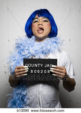 Stock Image - Mug shot of man in drag with blue wig and feather boa. Fotosearch