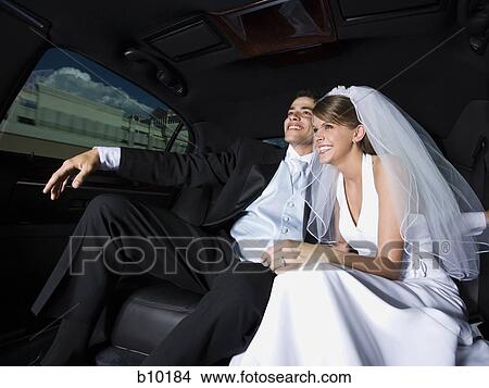 Picture - Newlywed couple sitting in a car and smiling. Fotosearch