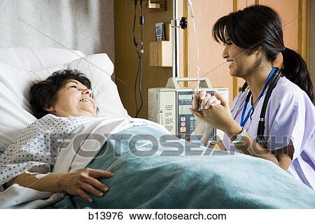 Nurse holding hand of mature woman in hospital bed View Large Photo Image Stock Photograph - Nurse holding hand of mature woman in hospital bed. Fotosearch