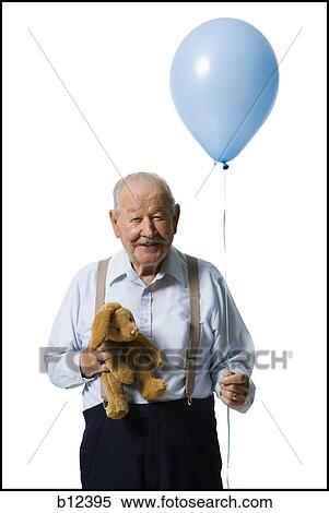 Stock Photography - Older man holding balloon and plush toy. Fotosearch