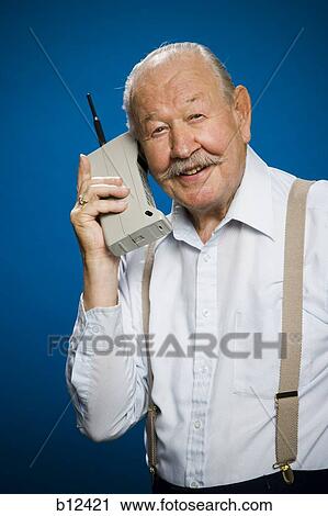 Stock Image - Older man making call on retro wireless phone. Fotosearch