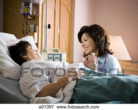 Older woman in hospital holding hands with woman smiling View Large Photo Image Stock Photo - Older woman in hospital holding hands with woman smiling. Fotosearch