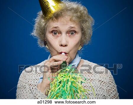 Older woman wearing a party hat blows a noisemaker View Large Photo Image Stock Photo - Older woman wearing a party hat blows a noisemaker. Fotosearch