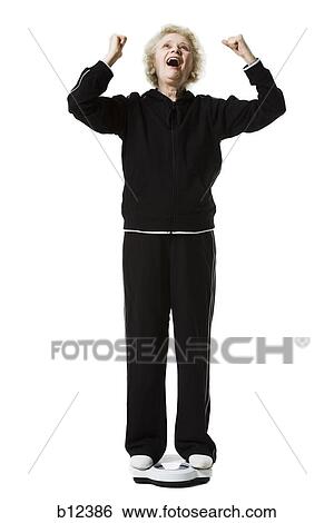 Stock Photograph - Older woman weighing herself on a bathroom scale. Fotosearch