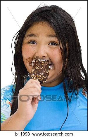 Stock Image - Overweight young girl eating ice cream bar. Fotosearch