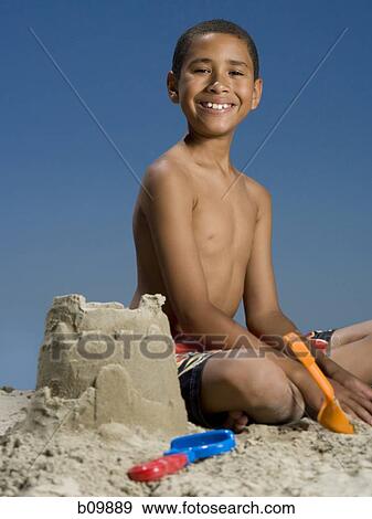 Portrait of a boy sitting beside a sand castle View Large Photo Image Stock Photo - Portrait of a boy sitting beside a sand castle. Fotosearch