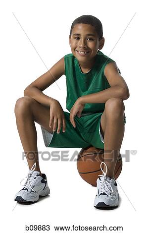 Stock Image - Portrait of a boy sitting on a basketball. Fotosearch