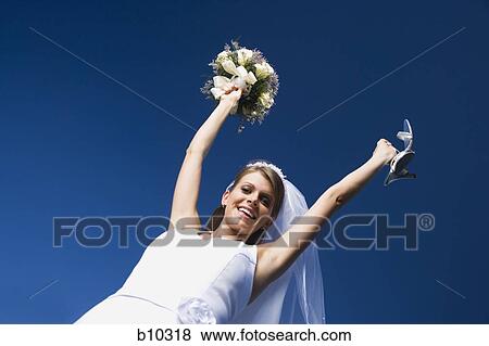 Stock Photo - Portrait of a bride holding a bouquet of flowers and a pair of sandals. Fotosearch