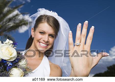 Stock Photo - Portrait of a bride showing her wedding ring and smiling. Fotosearch