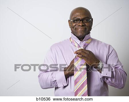 Portrait of a businessman tying his tie View Large Photo Image Stock Photograph - Portrait of a businessman tying his tie. Fotosearch