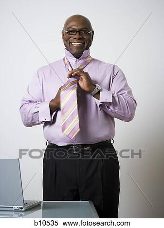 Portrait of a businessman tying his tie View Large Photo Image Stock Photography - Portrait of a businessman tying his tie. Fotosearch