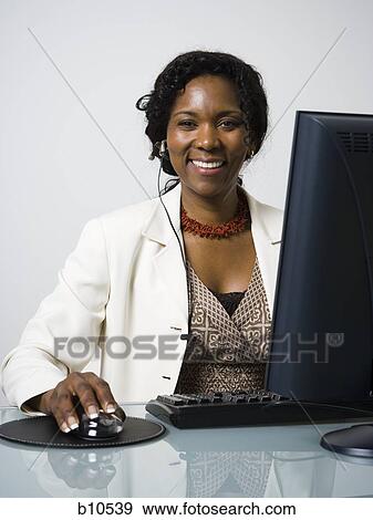 Stock Photo - Portrait of a businesswoman using a computer and smiling. Fotosearch