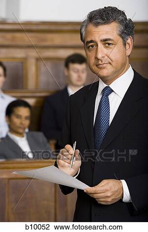 Stock Image - Portrait of a male lawyer standing in a courtroom during a trial. Fotosearch