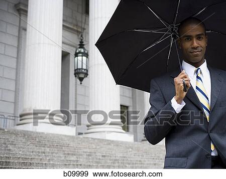 Portrait of a male lawyer standing in front of a courthouse and holding an umbrella View Large Photo Image Stock Photo - Portrait of a male lawyer standing in front of a courthouse and holding an umbrella. Fotosearch