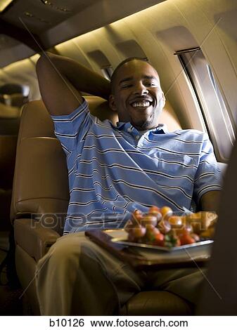Portrait of a man sitting in an airplane and smiling View Large Photo Image Stock Photograph - Portrait of a man sitting in an airplane and smiling. Fotosearch