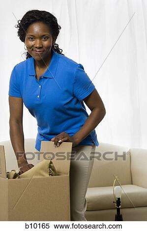 Stock Photography - Portrait of a senior woman unpacking a cardboard box. Fotosearch