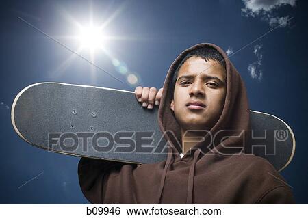 Portrait of a teenage boy carrying a skateboard View Large Photo Image Stock Photograph - Portrait of a teenage boy carrying a skateboard. Fotosearch