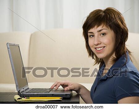 Portrait of a teenage girl using a laptop and smiling View Large Photo Image Stock Photo - Portrait of a teenage girl using a laptop and smiling. Fotosearch