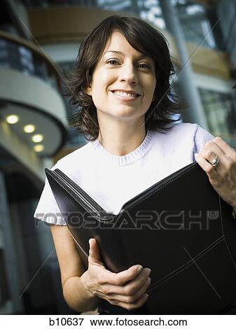 Portrait of a woman holding a file View Large Photo Image Stock Photo - Portrait of a woman holding a file. Fotosearch