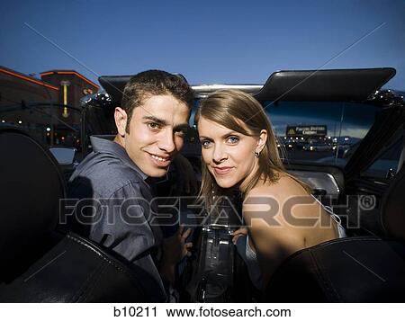 Stock Image - Portrait of a young couple sitting in a car and smiling. Fotosearch