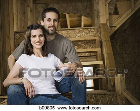 Stock Photography - Portrait of a young couple sitting on a staircase and smiling. Fotosearch