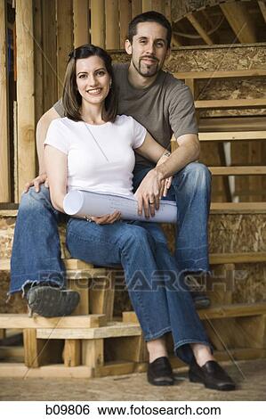 Stock Photograph - Portrait of a young couple sitting on the staircase and smiling. Fotosearch