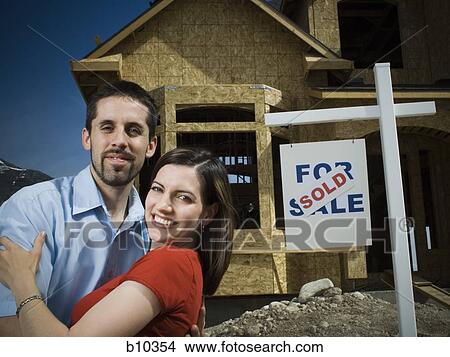 Portrait of a young couple smiling in front of a house View Large Photo Image Picture - Portrait of a young couple smiling in front of a house. Fotosearch