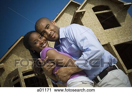 Portrait of a young man embracing a young woman in front of an unfinished home View Large Photo Image Stock Image - Portrait of a young man embracing a young woman in front of an unfinished home. Fotosearch