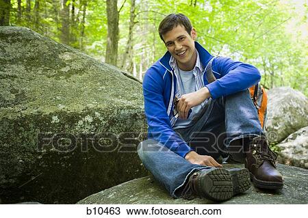 Stock Image - Portrait of a young man holding a chocolate bar and smiling. Fotosearch