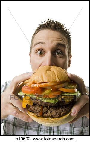 Portrait of a young man holding a hamburger View Large Photo Image Stock Image - Portrait of a young man holding a hamburger. Fotosearch